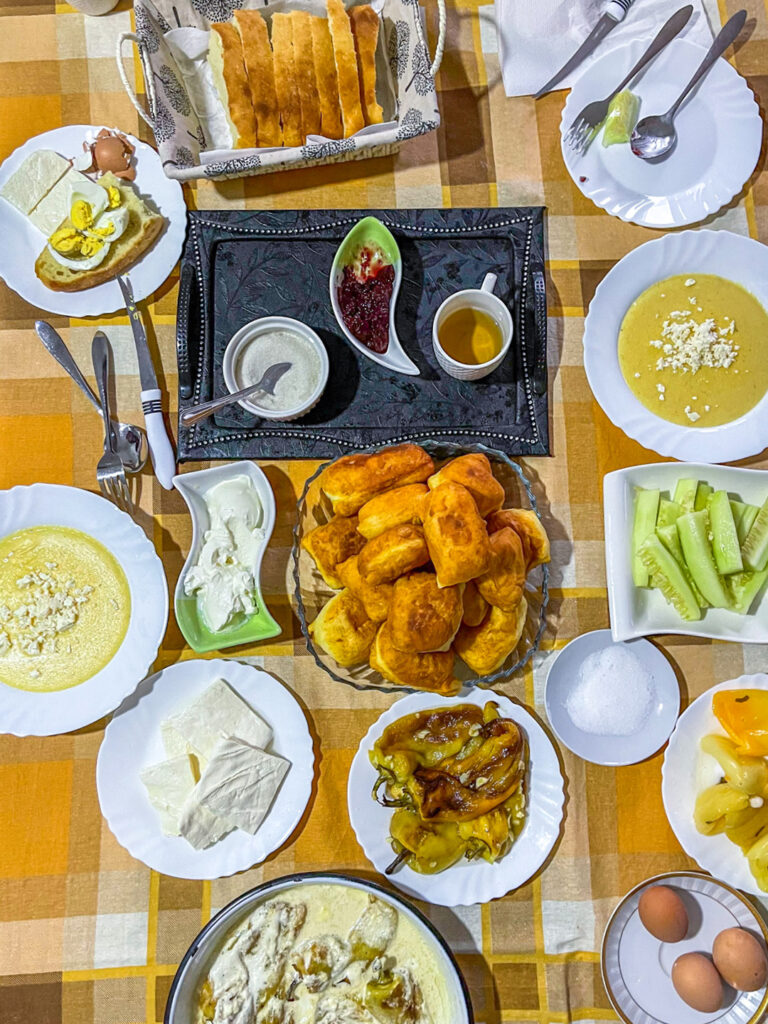 Man sieht einen gedeckten Tisch am Balkan mit regionalen Köstlichkeiten, wie Uštipci, Gemüse und gekochten Eiern. Er ist Teil der Verköstigung auf der Reise mit Weltweitwandern.