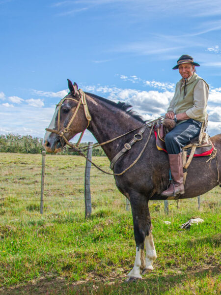 Ein Goucho sitzt auf seinem Pferd und lächelt in die Kamera der Wanderreisenden.