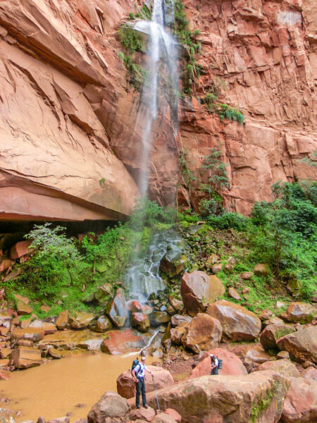 Mehrere Personen auf Wanderreise stehen neben einem Wasserfall in Südamerika auf ihrer Reise durch die Anden.