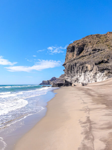Ein Sandstrand im Naturpark Cabo de Gata im Süden Spaniens. Im Hintergrund sieht man außerdem schroffe Klippen.