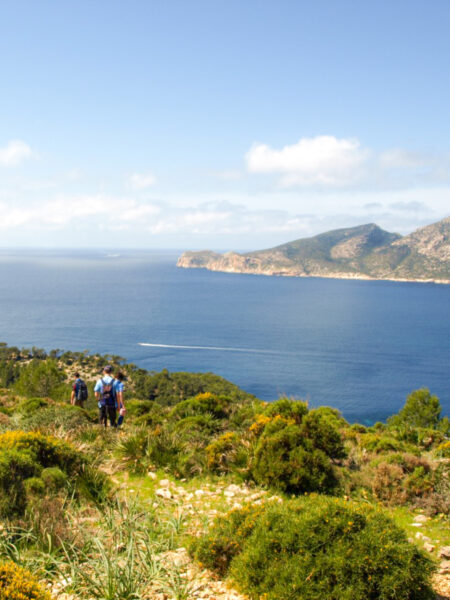 Zwei Personen stehen auf einem Wanderweg an der Nordküste von Mallorca und schauen auf die Küste im Mittelmeer hinaus.
