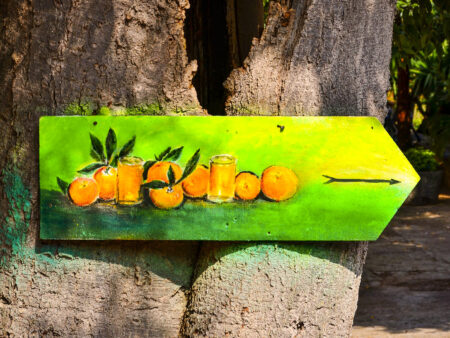 Ein Schild mit aufgemalten Orangen weist in die Richtung eines nahegelegen Orangenhains auf Mallorca.