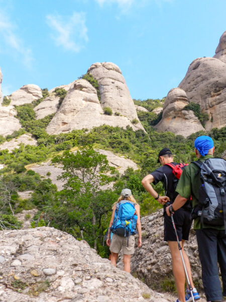 Mehrere Personen auf einer Wanderreise durch Nordspanien folgen einem felsigen Pfad in der Nähe des Kloster Montserrat.