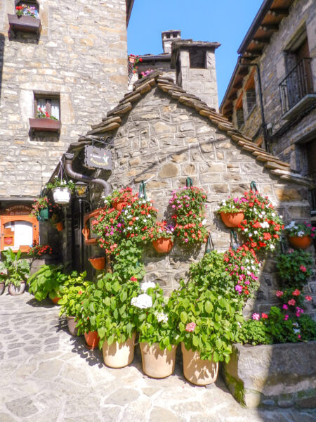 Ein mittelalterliches Steingebäude in der spanischen Ortschaft Torla. Vor dem Haus mit dem Giebeldach stehen einige Töpfe mit Kräutern und Blumen