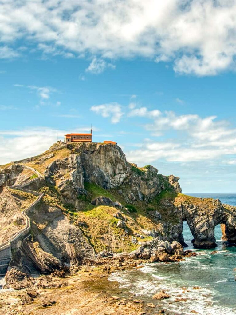 San Juan de Gaztelugatxe, eine Insel im Baskenland in Spanien vor dem Hintergrund des Himmels. Das Meer bricht an den steilen Klippen und die kleine Kapelle steht am höchsten Punkt der Insel.