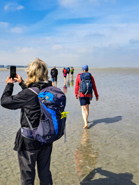 Eine kleine Reisegruppe mit Weltweitwandern wandert durch das Watt an der Nordküste von Frankreich.