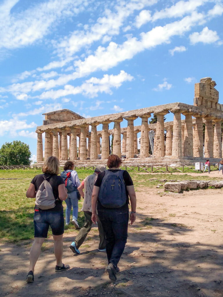Eine kleine Gruppe auf Wanderreise geht auf den Tempel der Athene in Peastum in Italien zu.