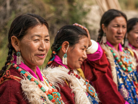 Eine Gruppe einheimischer Frauen aus Ladakh ist im Bild zu sehen. Sie schauen an der Kamera vorbei zu der Reisegruppe von Weltweitwandern.