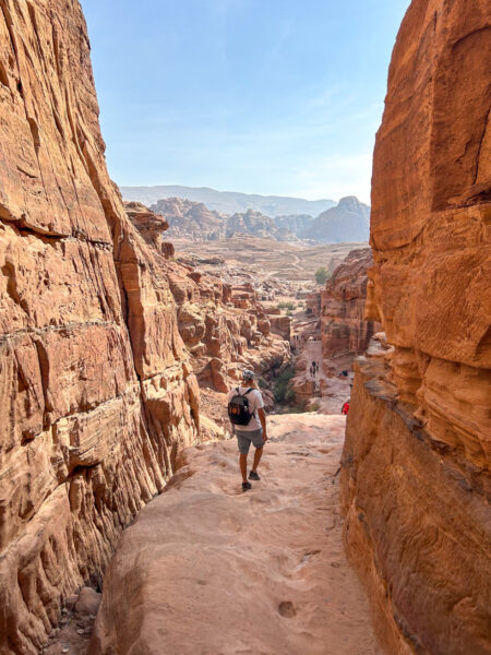 Ein Mann folgt dem Pfad zwischen Felswänden hindurch, der ihn auf seiner Wanderreise in Jordanien schließlich bis zu den Ruinen von Petra bringt.