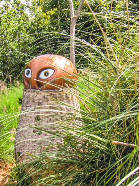 Eine Skulptur im Anima Garde in Marakesh steht halb versteckt hinter hohem Gras.