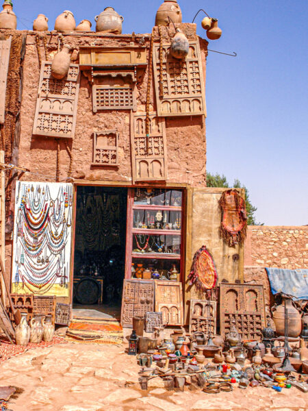 Ein Geschäft, das im Ksar von Aït-Ben-Haddou Kunsthandwerk verkauft. Es befindet sich in einem alleinstehenden Turm vor einem blauen Himmel.