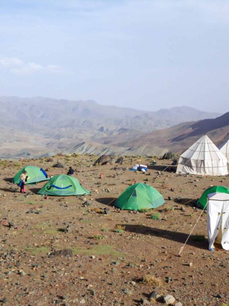 Auf dem Bild sehen wir mehrere Zelte eine Trekkingcamps einer Reisegruppe mit Weltweitwandern. Die Zelte stehen auf einen Ebene im Hohen Atlas in Marokko, hinter den Zelten verliert sich die Szene in den Wolken in der Ferne.
