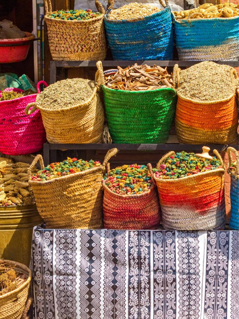 Mehrere Körbe mit getrockneten Kräutern, Blüten und Gewürzen stehen neben- und übereinander an einem Marktstand in Marrakesch.