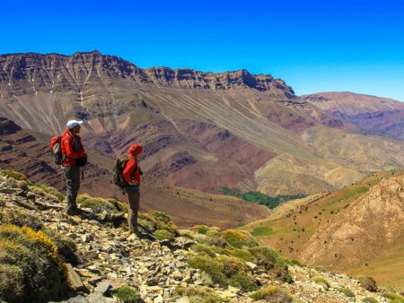 Zwei Wander-Reisende überblicken die Landschaft Marokkos im Hohen Atlas.