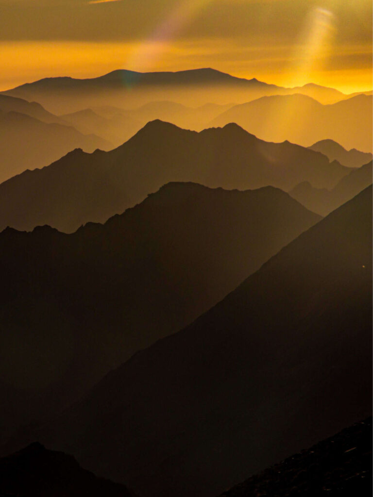 Auf dem Bild können wir den Sonnenauf- oder -untergang im Hohen Atlas in Marokko sehen. Das Foto wurde im Zuge einer Wanderreise durch den Gebirgszug in Marokko aufgenommen, vermutlich vom Camp der Trekkinggruppe von Weltweitwandern aus.