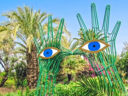 Ein Skulptur in den ANIMA Gardens in Marokko, die aussieht wie Hände mit großen Augen, die ein Tor bilden.