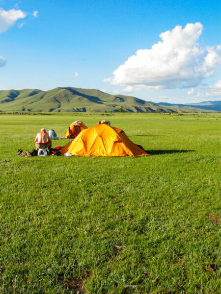 Ein Zelt eines Trekkingcamps von Weltweitwandern steht auf einer weiten, grünen Ebene in der Mongolei.