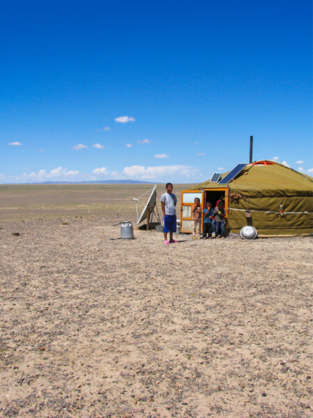 Man sieht eine Jurte in einer kargen Steppen- oder Wüstenlandschaft in der Mongolei.