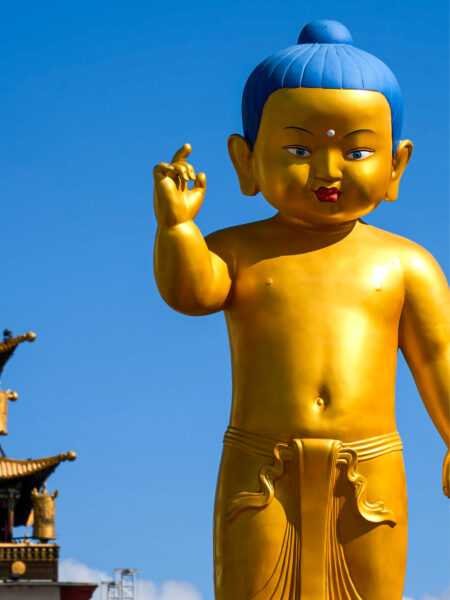 Eine Statue des Baby-Buddha. Die Statue hat eine Hand erhoben und scheint in die Kamera zu schauen. Das Foto wurde im buddhistische Gandan-Kloster in der Westmongolei aufgenommen.