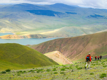Auf dem Bild wandert eine Gruppe durch die Westmongolei. Im Hintergrund kann einen der vielen großen See der Region erkennen.