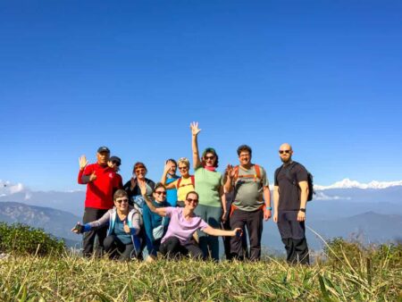 Auf dem Bild sieht man eine kleine Wandergruppe in Nepal, die vor einem Panorama posiert. Das Gruppenfoto zeigt einen der Höhepunkte ihrer Wanderreise in Nepal.