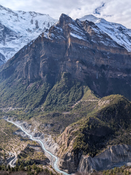 Eine Landschaftsaufnahme vom Annapurna Circuit in Nepal. Man blickt von einem Aussichtspunkt hinunter auf eine Schlucht, durch die der Marsyagndi-Fluss fließt.