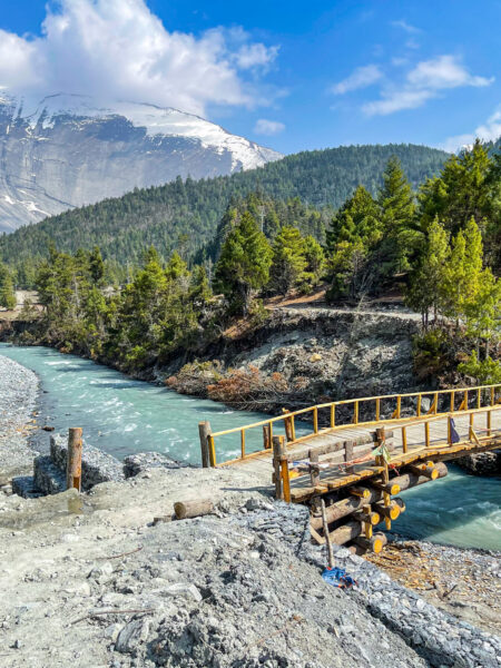 Eine Brücke, die Teil des Annapurna-Circuit, einer bekannte Trekking-Route durch den Himalaya ist, führt über einen schmalen Fluss.