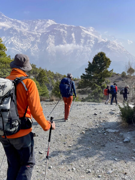 Eine kleine Wandergruppe auf einer geführten Trekking-Reise in Nepal, geht einem lokalen Guide hinterher, der sie über einen Teil des Annapurna-Circuit führt.