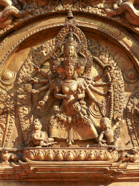 Das Bild zeigt den Türsturz (oder Torana) des goldenen Tors in Bhaktapur. Die Schnitzerei stellt die Göttin Taleju Bhawani dar, die sich durch vier Köpfe und zehn Arme auszeichnet.