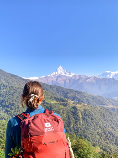 Eine junge Frau auf Wanderreise genießt den Ausblick in Nepal, auf ihrer Wanderung nach Dhampus.