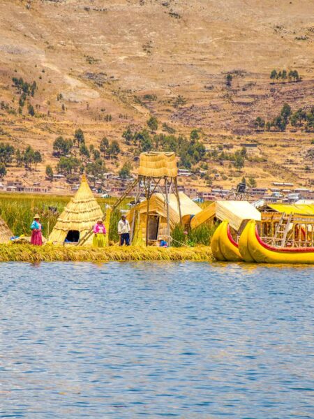 Man sieht die schwimmenden Inseln der Uros in Peru sowie mehrere ihrer bemalten Boote über das Wasser hinweg. Hier übernachten auch Gäste auf einer Weltweitwandern-Reise durch Peru.