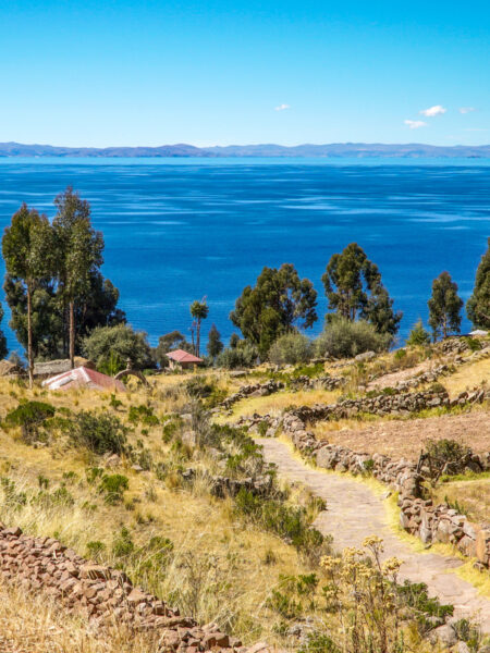 Man sieht einen Wanderweg auf der Insel Taquile im Titicacasee. Der Weg führt zum Ufer des Sees hinab.