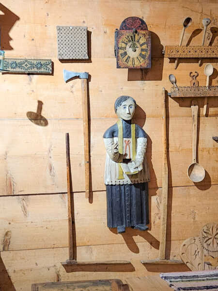 Kunstwerke und Werkstücke des traditionellen Holzschnitzers Jan Zieder im Goralen-Dorf Chocholow hängen an einer Wand. Reisende mit Weltweitwandern bekommen die Chance, seine Kunstwerke zur Gänze zu betrachten.