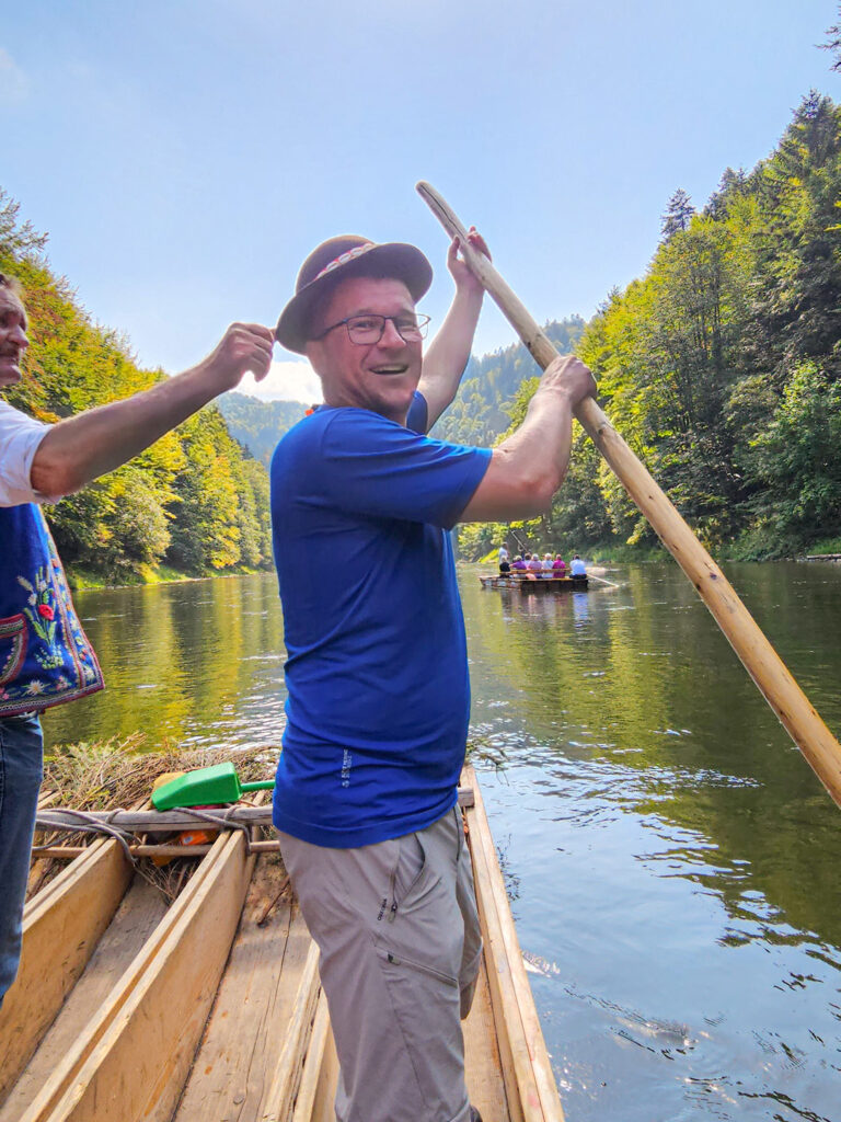 Ein Guide von Weltweitwandern steht auf einem Floß auf dem Fluss Dunajec an der polnisch-slowakischen Grenze. Zu beiden Seite der 