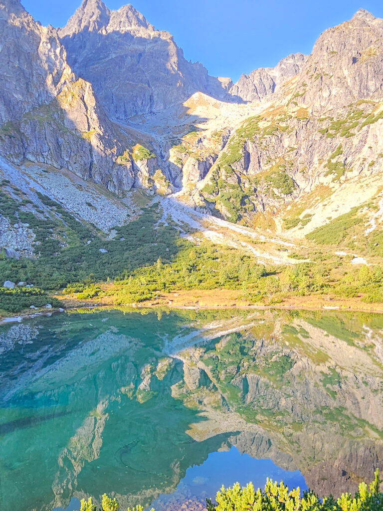 Ein Ausblick auf den Grünen See, den Zelené Pleso, in der Slowakei. Das Foto wurde aus dem Fenster einer Unterkunft hinaus aufgenommen und zeigt neben dem See auch die zerklüftete Bergkulisse der Tatra.