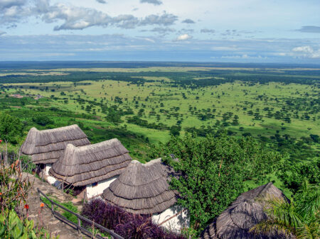 Rundhütten der Kingfisher Lodge mit Blick über die Savannenlandschaft Ugandas.