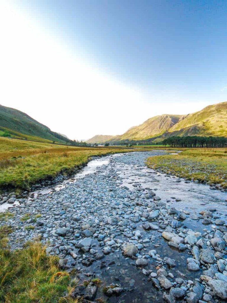 Auf dem Bild können wir wir einen Fluss inmitten der schottischen Highlands sehen. Das Wasser des Flusses ist seicht, die Region ist bekannt für die schönen Wanderunge, die man dort unternehmen kann.