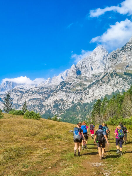 Eine kleine Gruppe an Personen wandert durch die albanische Landschaft in Richtung des Peja-Passes.