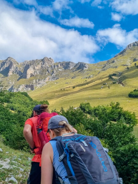 Zwei Personen auf Wanderreise gehen auf einem Weg in Albanien. Hinter ihnen kann man Teile des Berglands am Balkan erkennen.