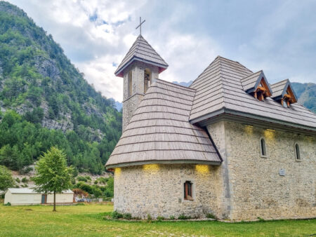 Die steinerne Kirche von Theth. Sie ist ein kleines Gebäude am Rande eines Wanderwegs.