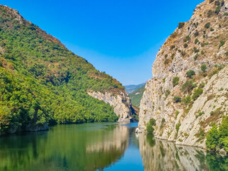 Der Koman-Stausee ist im Bild zu sehen. Er ist von beiden Seiten umgeben von hohen Felswänden bzw. einem dichten Wald.