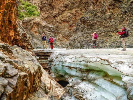 Eine kleine Gruppe Wander-Reisender steht auf dem ewigen Eis in der Geierschlucht in der Mongolei.