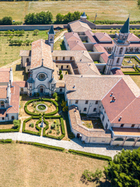 Eine Luftaufnahme des Certosa di San Bruno, oder San Bruno Klosters, in Sizilien. Man sieht mehrere Gebäude mit roten Dächern sowie einen kleinen Kirchturm. Im Zentrum des Bilder befindet sich auch eine gepflegte kleine Gartenanlage, die im Zuge einer Wanderreise mit Weltweitwandern besucht werden kann.