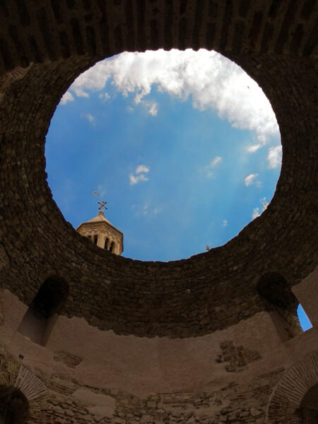 Ein Foto der runden Öffnung eines alten Turms nach oben hin. Durch die Öffnung hindurch kann man den Himmel über der kroatischen Split erkennen.