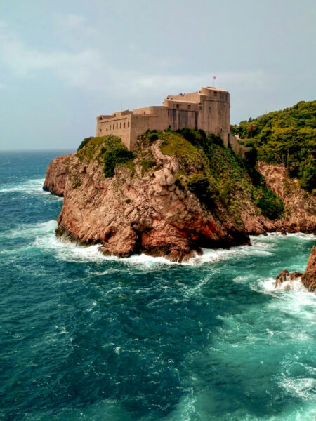 Ein Bild der Festung Lovrijenac in Dubrovnik, die über dem klaren Meer aufragt. Sie kann im Zuge einer Wanderreise mit Weltweitwandern besucht werden.