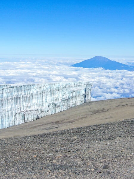 Ein Bild des Kilimandscharo-Massivs, das aus den Wolken über Tansania herausragt.