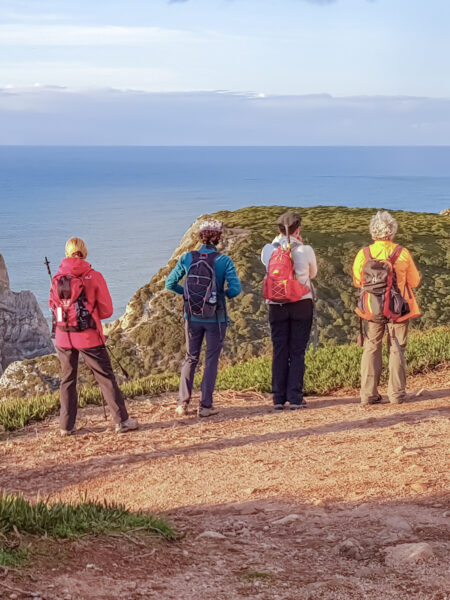 Ein Guide von Weltweitwandern und drei Personen auf Wanderreise stehen vor der Atlantik-Küste Portugals in der Nähe von Sintra. Sie schauen hinaus aufs Meer und genießen den Ausblick auf die endlosen Weiten des Atlantik.