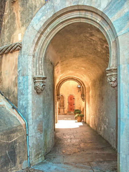 Ein Torbogen in Alentejo in Portugal ist von vorne erkennbar. Man sieht hindurch und erhascht im Hintergrund einen Blick auf eine Holztür.