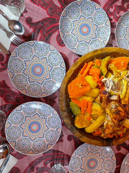 Man sieht einen Teller mit traditionellem marrokanischem Essen umrignt von den Tellern der Personen auf Wanderreise.