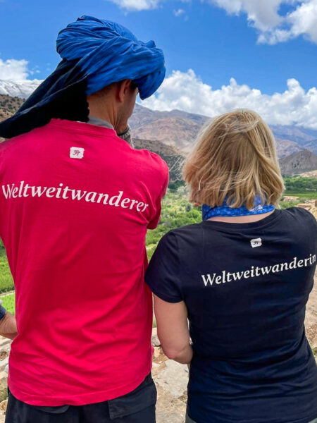 Zwei Personen, eine Guide und eine Touristin, stehen mit den T-Shirts von Weltweitwander vor einer Panorama-Aussicht in Marokko.
